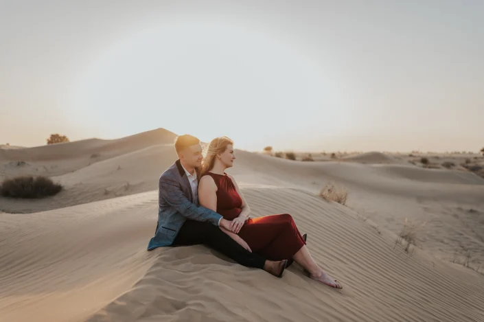 Couple sitting on a dune after their proposal in dubai