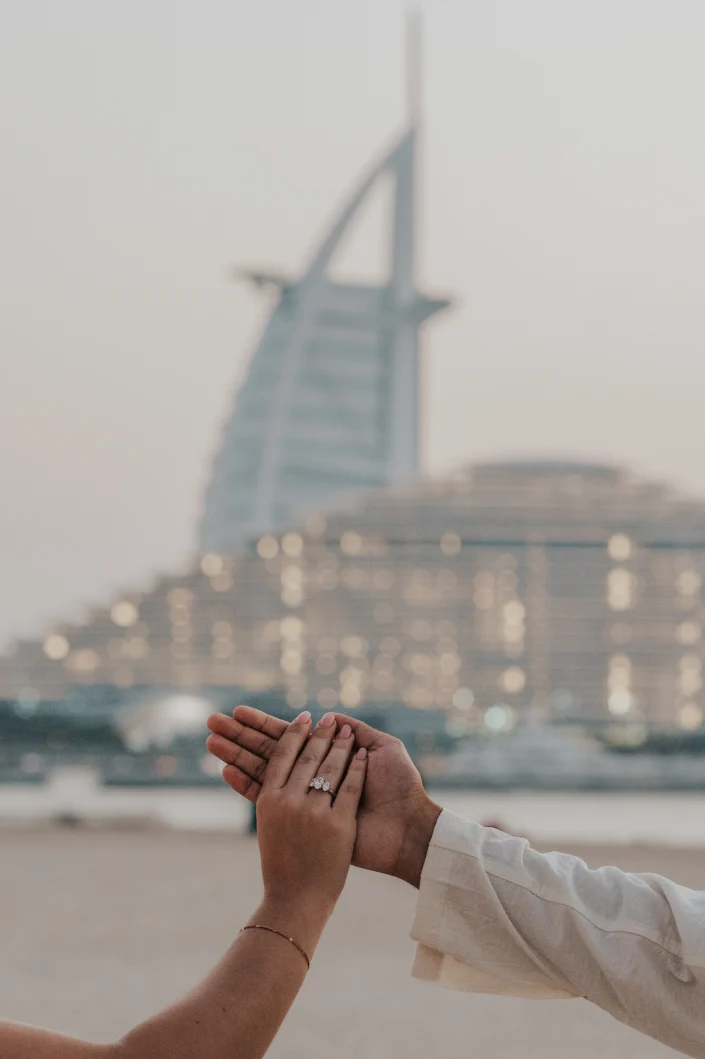 Hand holding shot with burj al arab in the background during a proposal in dubai